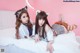 Two young women laying on a bed wearing cat ears.