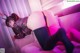 A woman in bunny ears is laying on a pink couch.