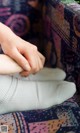 A person holding a pair of white socks on a couch.