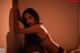 A woman in a black lingerie leaning against a wall.