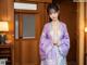 A woman in a purple kimono standing in a room.