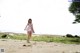 A woman in a pink dress walking on a sandy beach.