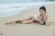 A woman in a white bikini laying on the beach.